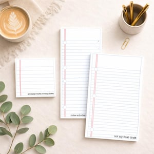 May include: A collection of lined paper pads with red margins and various text. One pad reads "probably worth writing down", another "notes adoodles", and the third "not my final draft". The pads are white with blue lines.