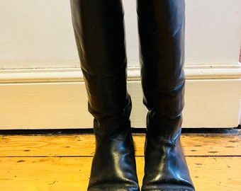 Un par de botas de montar vintage, largas, de cuero negro, 7F en la suela.