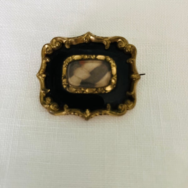 An antique mourning brooch, Georgian/Victorian, rectangular, black enamel, gilt, hair.