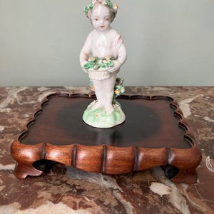 A wooden display stand, rectangular, vintage, solid dark wood, attractive scallop edge, a foot at each corner.