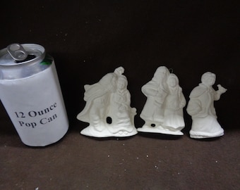May include: Four white ceramic Christmas decorations depicting people in winter clothing. The ornaments are approximately the size of a 355 ml can.