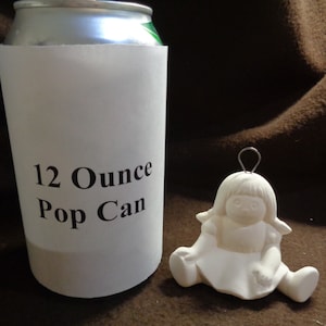May include: A white ceramic figurine of a girl sitting with her legs crossed. The figurine is 12 ounces and is the size of a standard pop can. The figurine has a wire loop on the top of her head for hanging.