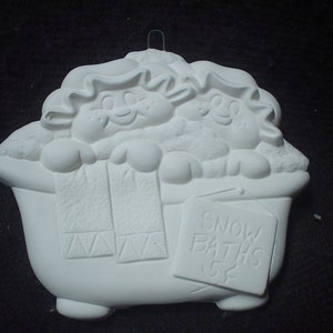 May include: White ceramic ornament of two cartoon characters taking a bath in a bathtub with the text "Snow Baths 52" on a sign.