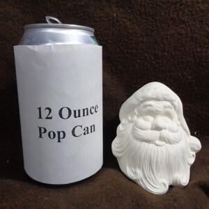 May include: White ceramic Santa Claus head ornament, approximately the size of a 12-ounce pop can. The ornament has a detailed face with a white beard and a red hat.