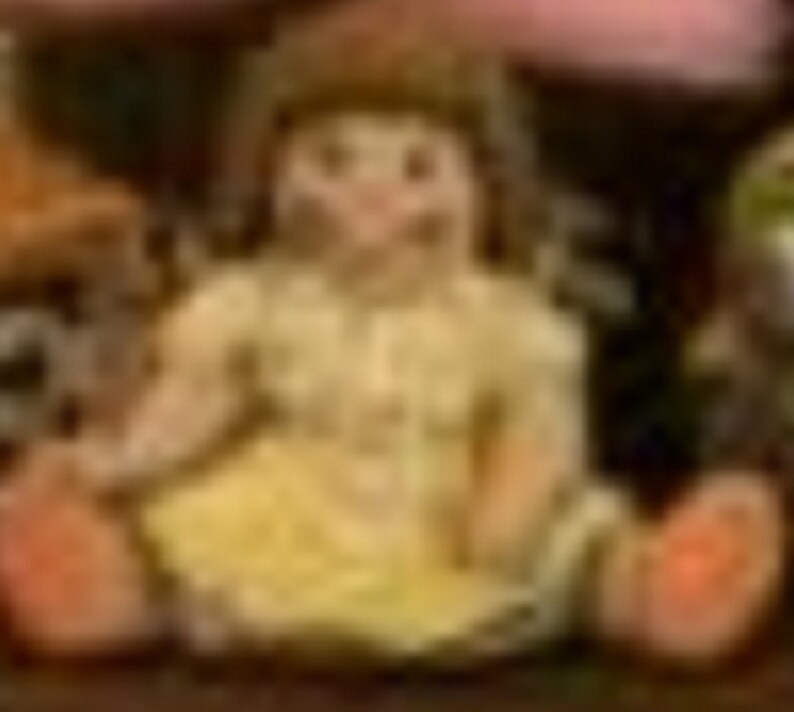 May include: A small porcelain doll wearing a yellow dress and with brown hair. The doll is sitting on a wooden surface.