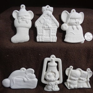 May include: Six white ceramic Christmas ornaments featuring a mouse theme. The ornaments include a mouse in a stocking, a mouse in a house, a mouse in a coat, a mouse sleeping on a log, a mouse in a lantern, and two mice on a swing.