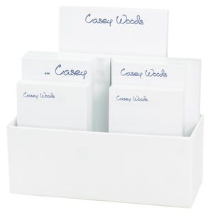 May include: White desk organizer with five white notepads. The notepads have the text "Casey Woods" written in blue ink.