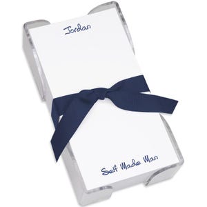 May include: A clear acrylic notepad holder with a stack of white notepad paper. The notepad has the name "Jordan" and the text "Self Made Man" printed on it. A navy blue ribbon is tied around the notepad holder.