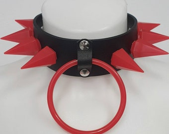 May include: A black leather choker with red plastic spikes and a red plastic ring.