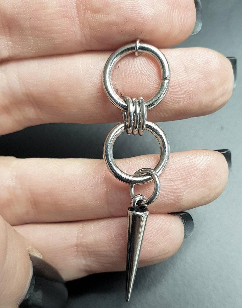 May include: Silver double hoop earring with a sharp, pointed spike charm hanging from the bottom.