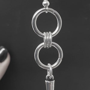 May include: Silver dangle earrings with two connected circles and a pointed spike charm.