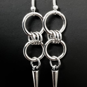 May include: Silver earrings with multiple linked rings and a pointed spike pendant.