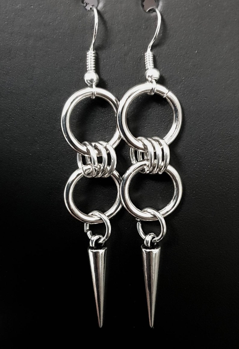 May include: Silver earrings with multiple linked rings and a pointed spike pendant.