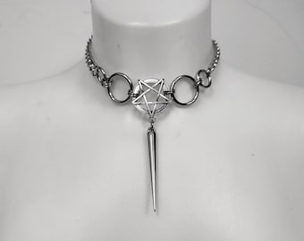 Puede incluir: Un collar choker plateado con un colgante de pentagrama y una larga punta puntiaguda que cuelga del centro.