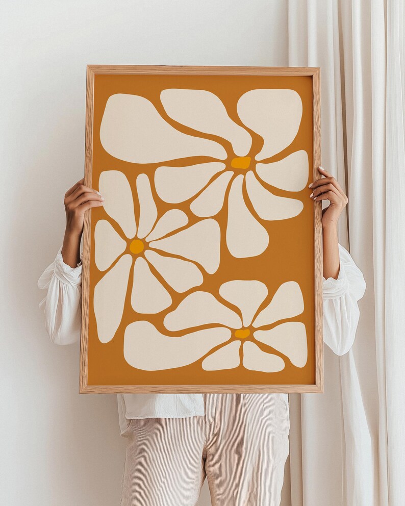 May include: A framed print with a minimalist design featuring three stylized white flowers with yellow centers on a mustard yellow background.