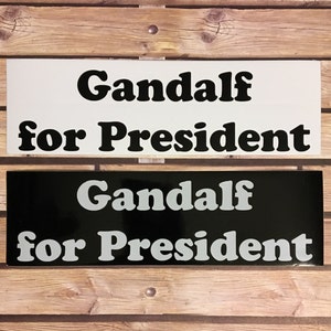 May include: Two black and white signs with the text "Gandalf for President" in a retro font. The top sign has black text on a white background, and the bottom sign has white text on a black background.