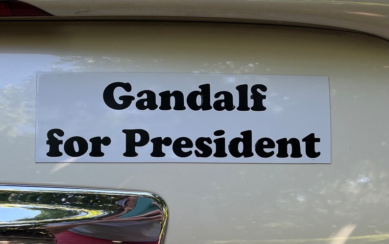 May include: A white bumper sticker with black text that reads "Gandalf for President".