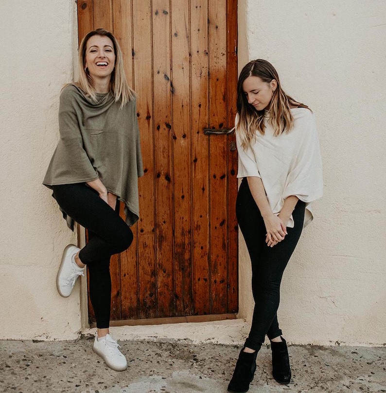 Peut inclure: Deux personnes portant des ponchos, l'un en vert et l'autre en blanc, se tiennent devant une porte en bois. Elles portent toutes les deux un pantalon noir et des chaussures.