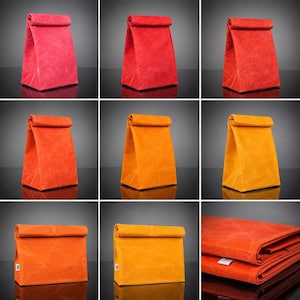 May include: A collection of nine images displaying roll-top lunch bags in various shades of red, orange, and yellow. The bags feature a textured, creased surface and a rectangular base. One image shows a bag folded flat with a small white tag.
