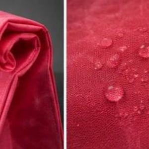 May include: A vibrant red fabric with a smooth, folded texture on the left side and a close-up view of the material on the right side, featuring multiple clear water droplets resting on the surface, demonstrating a water-resistant quality.