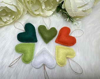 May include: Six felt heart ornaments in various colors, including green, yellow, orange, and white. Each heart has a string loop for hanging.