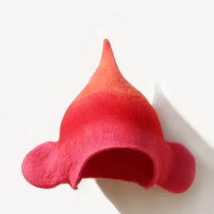 May include: A red and pink felt hat with a pointed top and two small ear flaps.