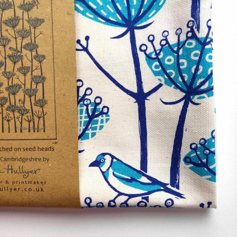 Peut inclure: Un tissu blanc avec un motif floral bleu et turquoise. Le tissu pr&eacute;sente un oiseau stylis&eacute; avec un corps bleu et des ailes turquoise. Le texte "Hullyer" est imprim&eacute; sur l'&eacute;tiquette en papier brun.