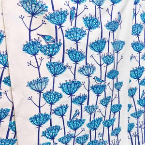 Peut inclure: Un tissu blanc avec un motif floral bleu et blanc. Les fleurs sont stylis&eacute;es et ont un design g&eacute;om&eacute;trique. De petits oiseaux bleus sont perch&eacute;s sur les fleurs.