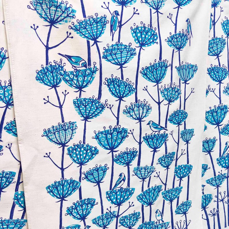 Peut inclure: Un tissu blanc avec un motif floral bleu et blanc. Les fleurs sont stylis&eacute;es et ont un design g&eacute;om&eacute;trique. De petits oiseaux bleus sont perch&eacute;s sur les fleurs.