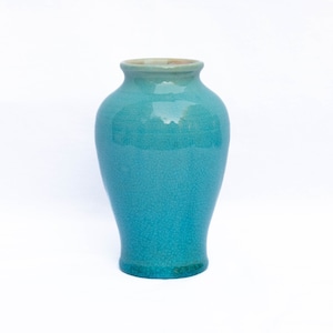 May include: A turquoise ceramic vase with a textured glaze. The vase has a rounded body and a narrow neck.