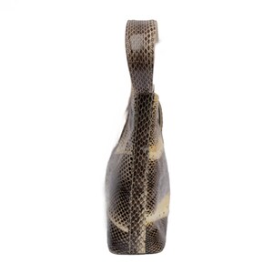 May include: A snakeskin-patterned handbag with a single handle. The bag features a mix of brown, gray, and cream tones, creating a textured appearance. The handle is a continuation of the bag's material, and the bag is set against a white background.