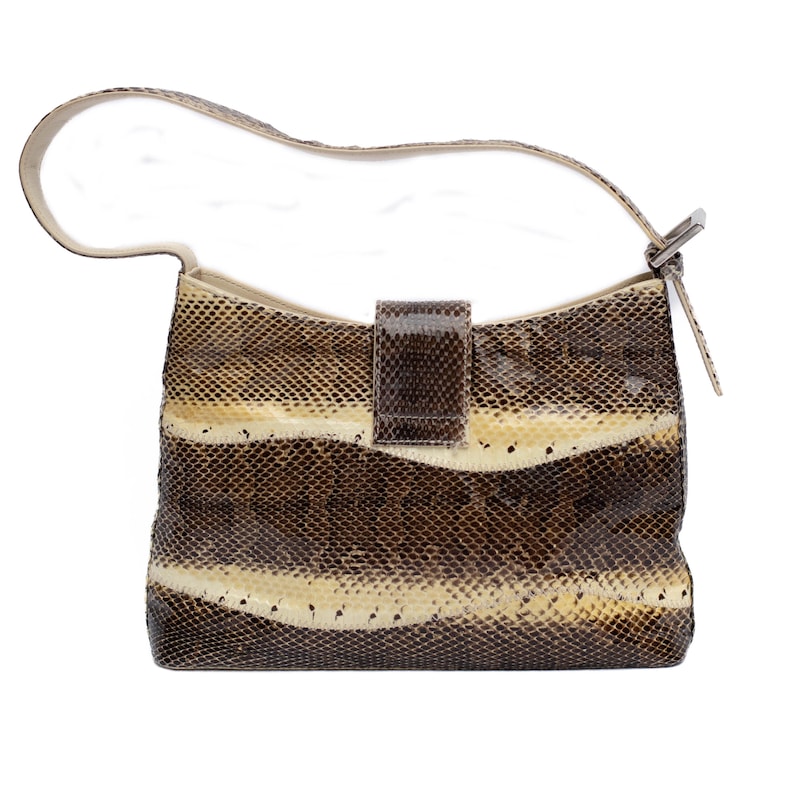 May include: A snakeskin-patterned handbag with a cream-colored strap and a rectangular flap closure. The bag features horizontal bands of brown, tan, and cream colors. The strap is attached to the bag with a silver-colored metal buckle.