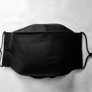 May include: A black cloth face mask with adjustable ear loops. The mask is made of a soft, breathable fabric.
