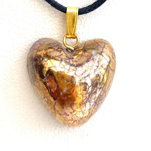 Colgante o collar de cerámica con corazón dorado.