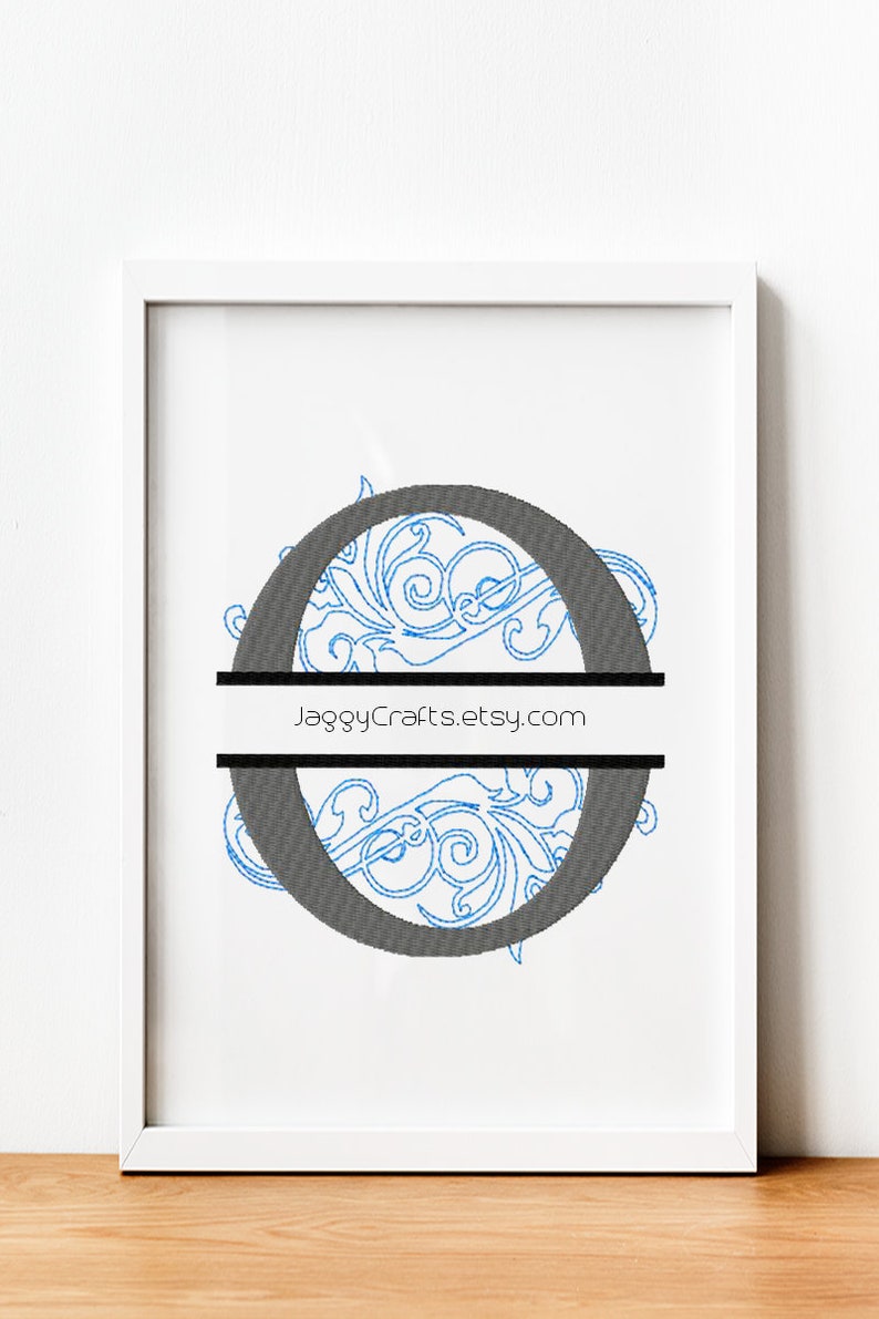 K&ouml;nnte beinhalten: Ein wei&szlig;er Rahmen mit einem wei&szlig;en Passepartout, der einen gestickten Buchstaben "O" in Blau und Grau mit einer dekorativen Verzierung umgibt. Der Buchstabe ist mit einer schwarzen Linie in zwei H&auml;lften geteilt und der Text "JaggyCrafts.etsy.com" ist auf die Linie gedruckt.