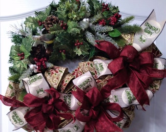 May include: A Christmas wreath with red and gold ribbon, green pine branches, red berries, and a small bird. The ribbon has the text "Merry Christmas" printed on it.