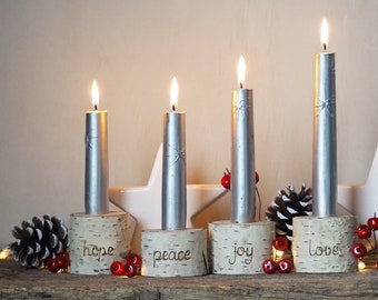 May include: Four silver candles with a star design on the side are placed in wooden candle holders. The holders are decorated with the words "hope", "peace", "joy", and "love".