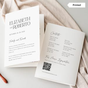 May include: A white wedding invitation with black text. The invitation reads "Elizabeth and Roberto" and "October 26-28, 2026". The invitation also includes a section titled "Family and Friends" with a welcome message and a section titled "Contacts" with a list of names and phone numbers.