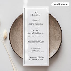 May include: A wedding menu card with a black border, featuring the text "THE MENU" at the top. The menu lists salad, entree, and dessert options. The card is on a brown plate. The names "Charlotte and Richard" and the date "SEPTEMBER 15, 2026" are at the bottom.