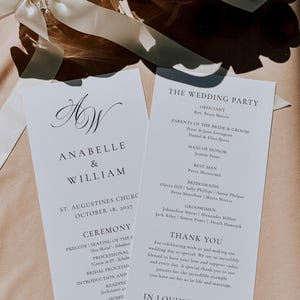 Peut inclure: Deux programmes de cérémonie de mariage blancs avec une typographie noire à empattement et manuscrite. La carte de gauche présente les noms Anabelle & William, la date du 18 octobre 2027 et le détail de la cérémonie. La droite liste les invités.