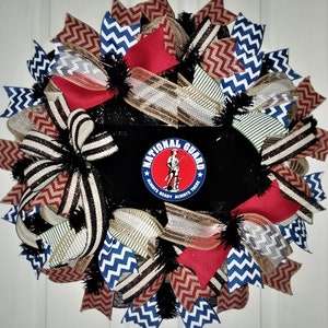 May include: A red, white, and blue wreath with a black background and a National Guard logo that says "Always Ready, Always There".