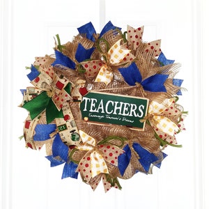 May include: A burlap wreath decorated with blue, yellow, and red ribbon bows. The wreath has a green sign that says "TEACHERS Encourage Tomorrow's Dreams".