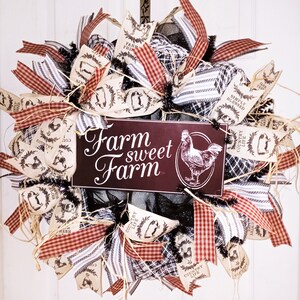 May include: A farmhouse-style wreath with a burgundy sign that reads "Farm sweet Farm" and features a rooster illustration. The wreath is decorated with burlap ribbons, red and white checkered ribbons, and ribbons with farm-themed illustrations.