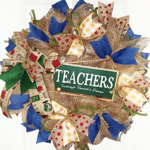 May include: A burlap wreath decorated with blue, green, and yellow bows. The wreath has a chalkboard sign that says "TEACHERS Encourage Tomorrow's Dreams".