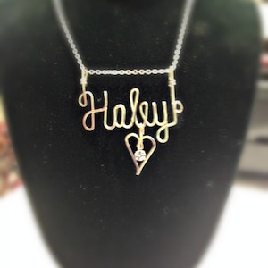 May include: A gold necklace with a heart pendant and the name "Haley" spelled out in wire.