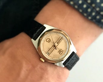 珍しい文字盤のヴィンテージ男性用腕時計「Raketa」（英語でロケット）は、文字盤に日付表示のある機械式時計です。新しい革バンドが付属します。