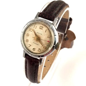 May include: A silver wristwatch with a white face and black Roman numeral hour markers. The watch has a brown leather strap and a gold-coloured second hand.