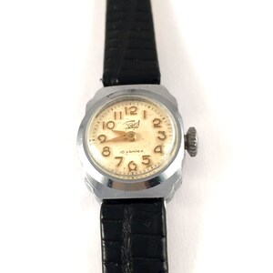 May include: A silver wristwatch with a white face and black leather band. The watch face has black Roman numeral hour markers and gold Arabic numeral minute markers. The watch face also has the text "16 камней" in gold lettering.