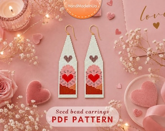 May include: A pair of long, triangular seed bead earrings featuring a white background with a central red heart, a pink circular motif, and a dark red base. The earrings hang from gold-toned metal hooks and display a pixelated, woven texture.