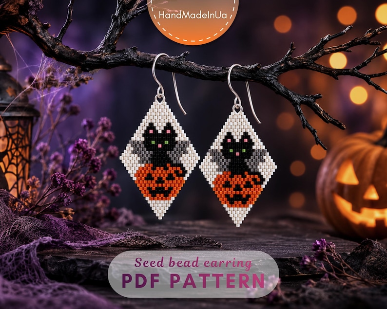 May include: A pair of diamond-shaped seed bead earrings featuring a black cat with grey wings sitting on an orange jack-o'-lantern against a white background. The earrings hang from silver-toned metal hooks. The text reads Seed bead earring PDF PATTERN.
